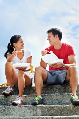 A smiling couple in fitness clothing sitting on a set of steps e